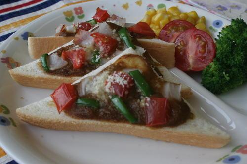 残ったカレーを食パンに塗り、その上にカットした好きな野菜をのせ粉チーズをふりかけてオーブントースターで焼いたカレーピザトーストの写真