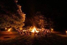 夜にキャンプファイヤーの周りを囲む人