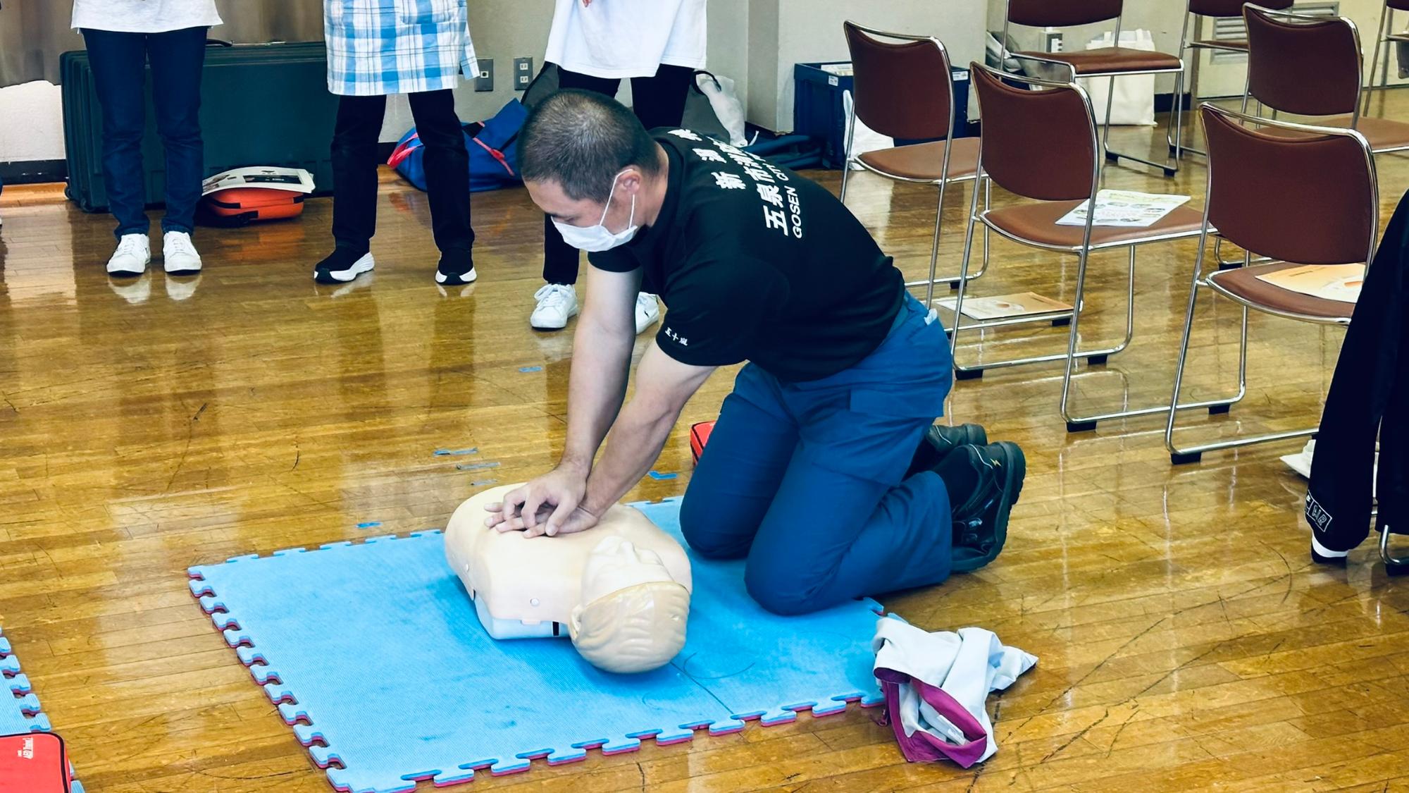 普通救命講習で講師が心肺蘇生法とAEDの使い方の見本を見せている