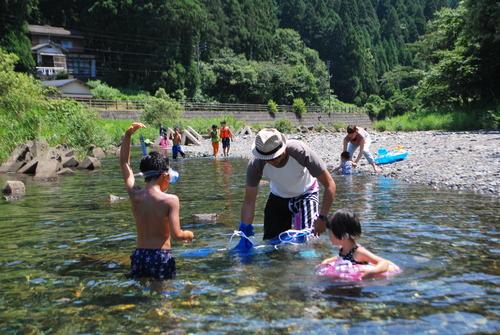 仙見川ふるさとづくり河川公園で家族などが川遊びをしている様子の写真