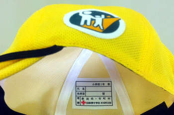 黄色い交通安全帽子のタグに赤十字と表示されている写真